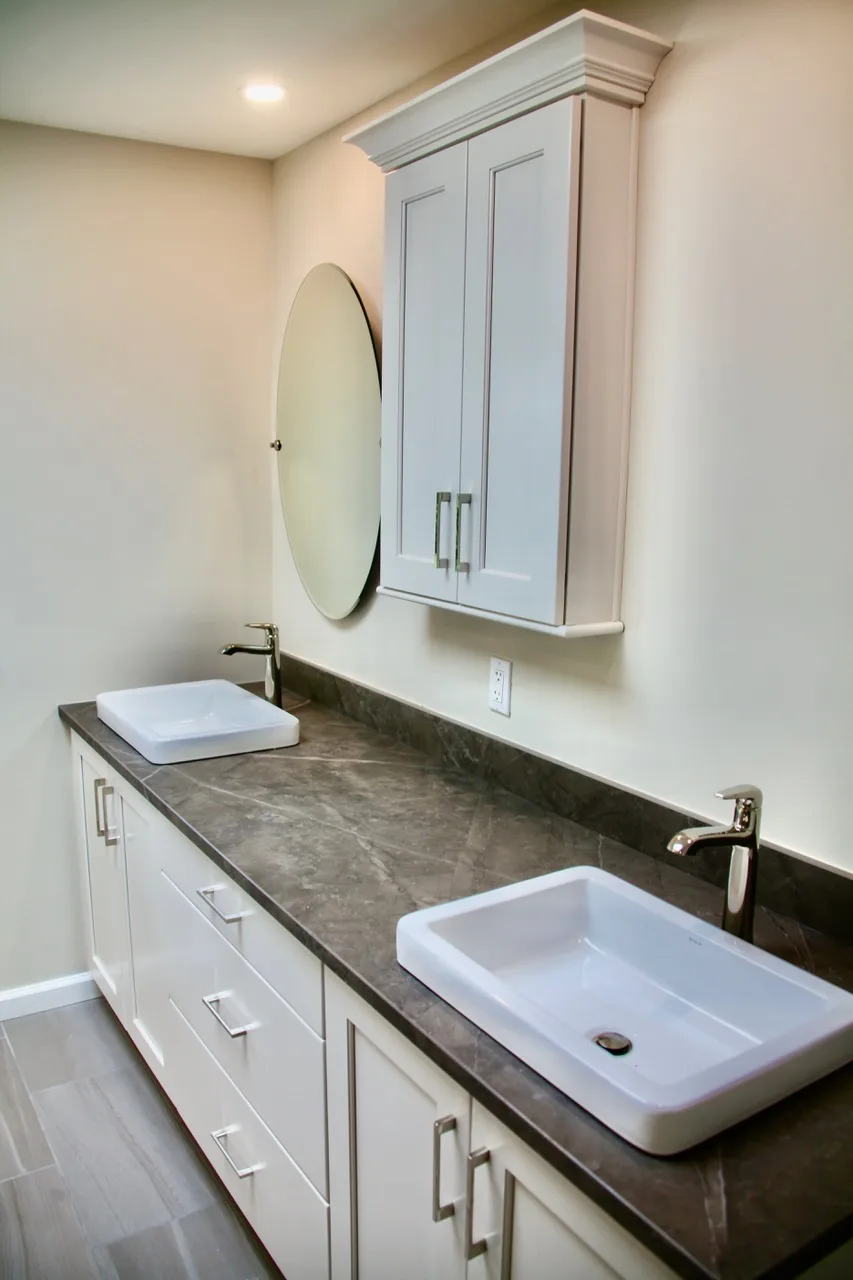 Custom bathroom vanity with dual vessel sinks, soapstone counter and round mirror by Mac Kitchens in the Lehigh Valley