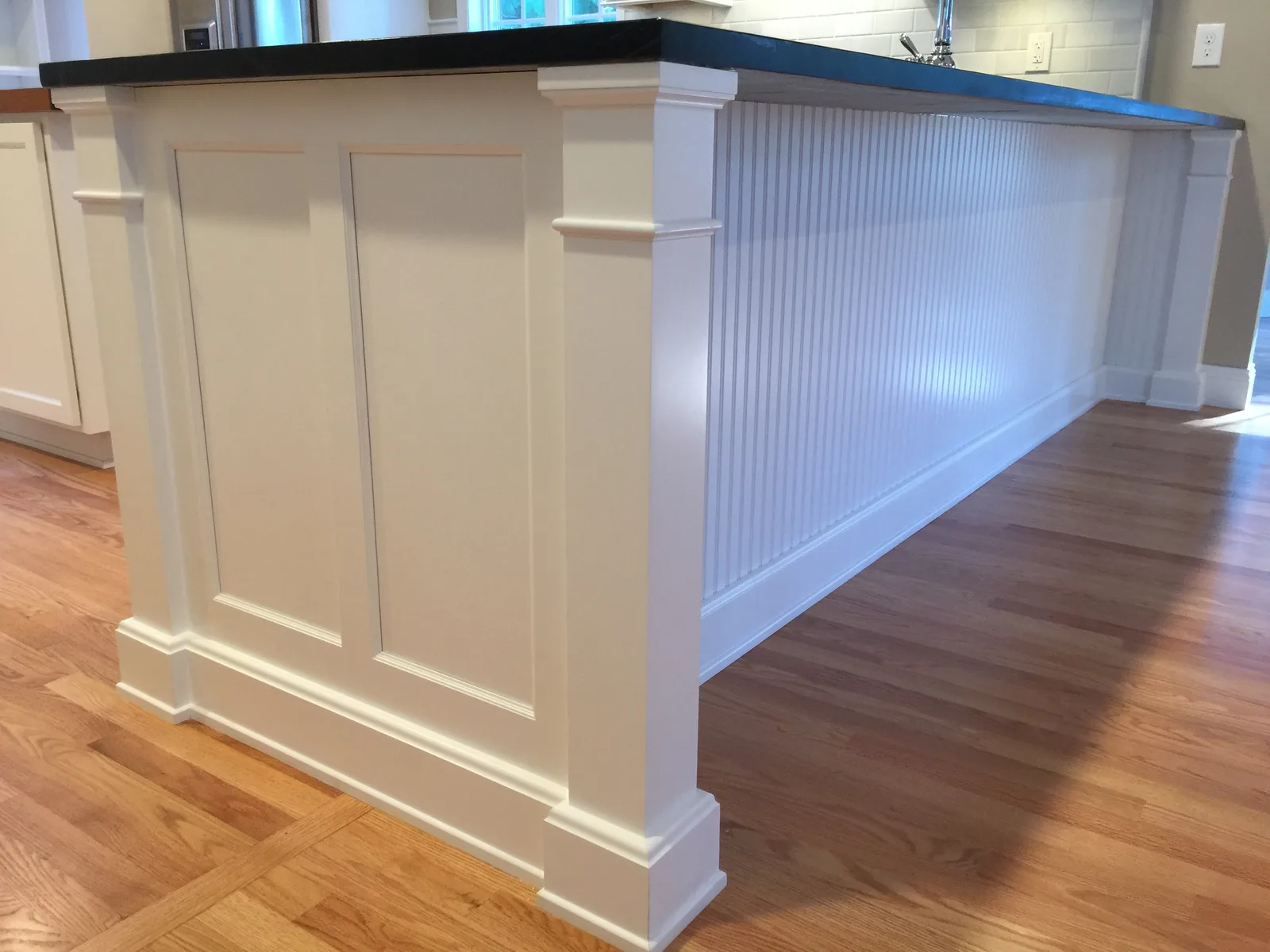 A hand-built custom kitchen island with raised-panel ends and a beadboard back by Doug MacGeorge of Mac Kitchens